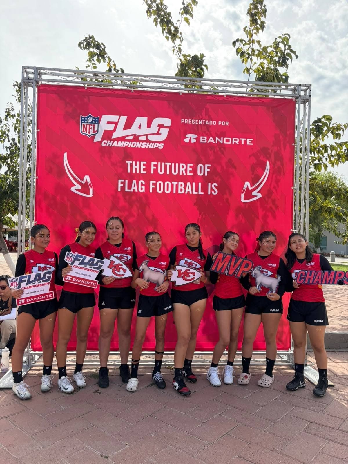 Las jugadoras de Kansas posan juntas frente al fondo de NFL Flag Championships